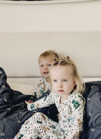 Baby Girl and Baby Boy in Bashbot Footie Sitting on a Bed